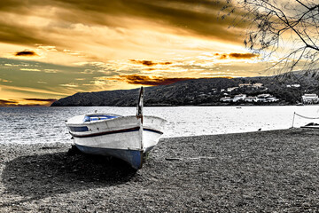 Typical fishing boat on the beach at sunset in the picturesque coastal town of Cadaqués, Costa Brava, Girona. Black and white effect