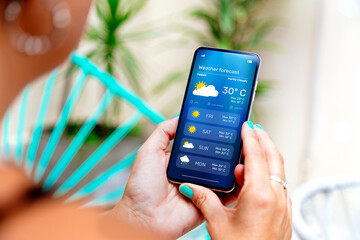 Woman outdoors checking the weather forecast on an app on her mobile phone.
