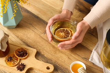 Young woman holding cup with green tea  with lemon in kitchen
