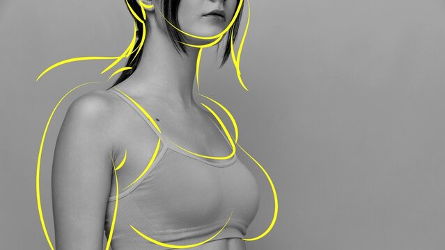 Cropped image of female body, breast in sports bra with yellow contour lines on grey background. Weight loss and health checkup. Concept of body and health care, wellness, body-positivity, diet, sport