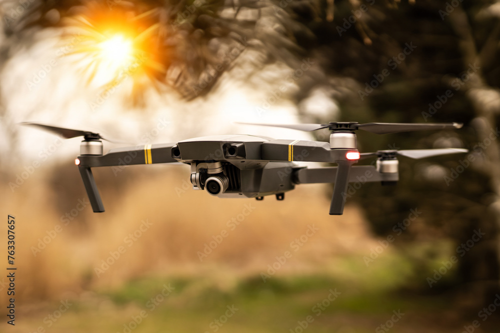 Wall mural man operating drone/man holding remote control drones/drone controller with sunset background.