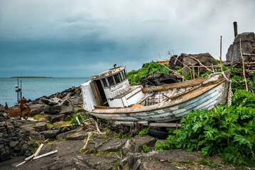Old boat wreck on the shore near recycled house in Iceland