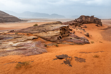 Red rocks and red sand in Wadi Rum desert. Martian landscape. Rainy clouds. Jordan
