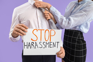 Business man holding paper with text STOP HARASSMENT and his female colleague on lilac background,...