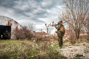 Survivor soldier in hood with svd rifle walking in the danger radioactive zone in ruins of...