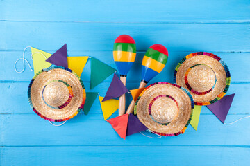 Mexican holiday background with serape striped blanket or poncho, sombrero hat, maracas on old blue wood backdrop. Mexico Cinco de Mayo festival, Mexican Independence day background
