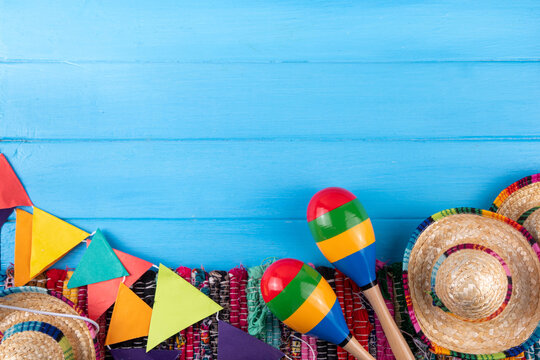Mexican holiday background with serape striped blanket or poncho, sombrero hat, maracas on old blue wood backdrop. Mexico Cinco de Mayo festival, Mexican Independence day background