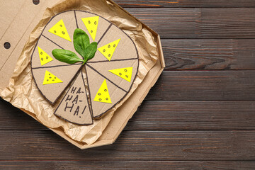 Carton pizza on wooden background. April Fools Day prank
