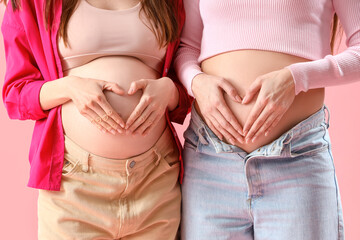 Pregnant female friends on pink background, closeup