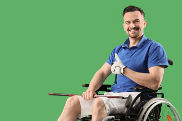 Handsome man in wheelchair with golf club showing thumb-up on green background