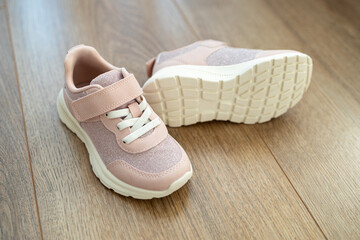 Child's pink sneakers on wooden floor. Cute girl's shoes on floor - 763320400