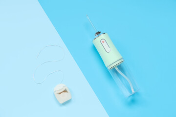 Oral irrigator and dental floss on color background
