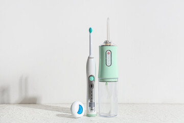 Oral irrigator, electric toothbrush and dental floss on white background