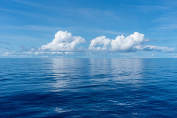 Beautiful blue sky, with fluffy clouds over the calm Pacific Ocean. 