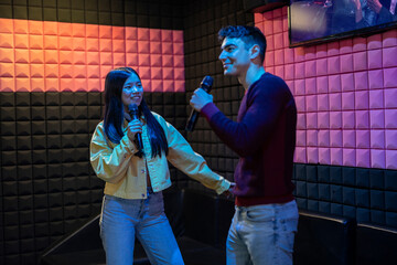 multiethnic couple singing and dancing in karaoke - first date after meeting on dating app
