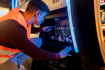 computer engineer mechanic fixing arcade game machines in an arcade - mechanical routine inspection checkup