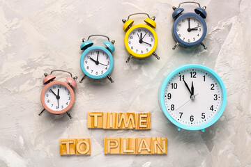 Text TIME TO PLAN with colorful alarm clocks on grey background. Time management. Top view