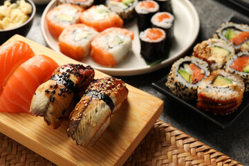 Different tasty sushi rolls on dark grey table