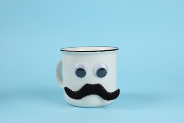 Man's face made of cup, fake mustache and decorative eyes on light blue background