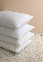 Fototapeta na wymiar Stack of soft white pillows near beige wall indoors