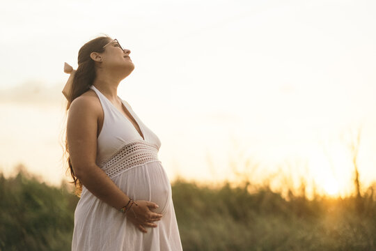 Mujer embarazada al aire libre durante el atardecer