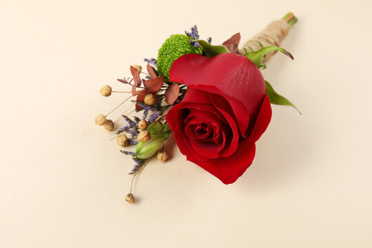 Stylish boutonniere with red rose on beige background, closeup