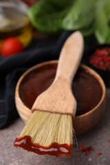 Marinade in bowl and basting brush on brown table, selective focus