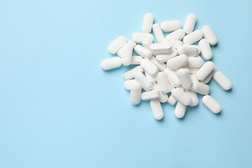 Vitamin pills on light blue background, top view. Space for text
