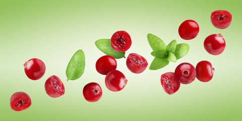 Fresh red cranberries and leaves flying on green background