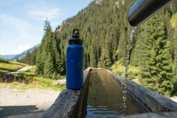  Refilling Blue Water Bottle at Mountain Spring for Sustainable Travel - 763332036