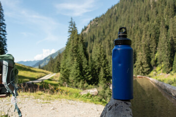 : Blue Water Bottle on Wooden Bench in Mountainous Landscape - 763332051