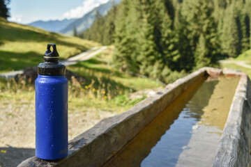 : Blue Water Bottle on Wooden Bench in Mountainous Landscape - 763332066