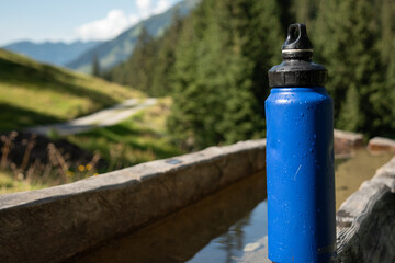 : Blue Water Bottle on Wooden Bench in Mountainous Landscape - 763332071