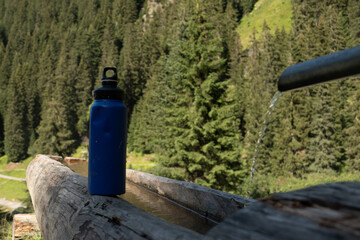: Blue Water Bottle on Wooden Bench in Mountainous Landscape - 763332072