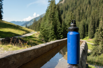 : Blue Water Bottle on Wooden Bench in Mountainous Landscape - 763332078