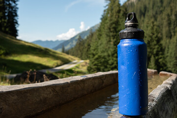 : Blue Water Bottle on Wooden Bench in Mountainous Landscape - 763332087