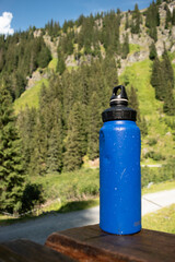  Reusable Blue Water Bottle on Rustic Wooden Surface with Alpine Background - 763332204