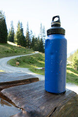: Blue Water Bottle on Wooden Bench in Mountainous Landscape - 763332221