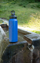 : Blue Water Bottle on Wooden Bench in Mountainous Landscape - 763332224