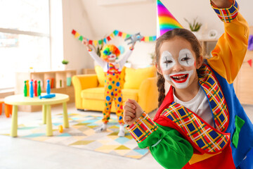 Funny little girl in clown costume at home. April Fools' Day celebration
