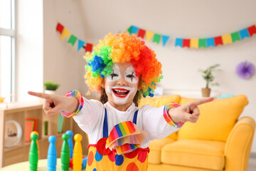 Funny little girl in clown costume pointing at viewer, closeup. April Fools' Day celebration