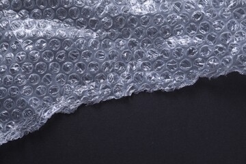 Transparent bubble wrap on black background, top view. Space for text