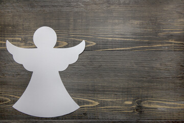 A cute white angel silhouette on a wooden background with copy space/space for text.