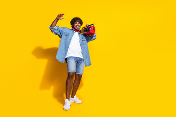 Full body photo of attractive young man boombox music cheerful wear trendy denim clothes red scarf isolated on yellow color background