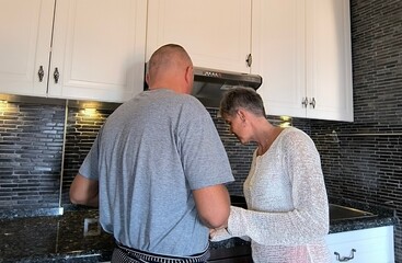 Happy couple cooking together.  Husband and wife in their kitchen at home preparing healthy...