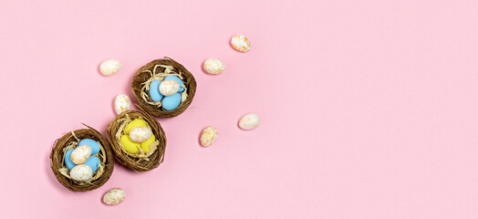 Top view Easter eggs in nest on pink background. Wide banner.