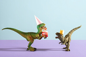 Cute happy dinosaurs in birthday hats holding cake with flaming candles on blue violet background.