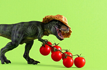 Dinosaur in straw hat with tomatoes on green background.