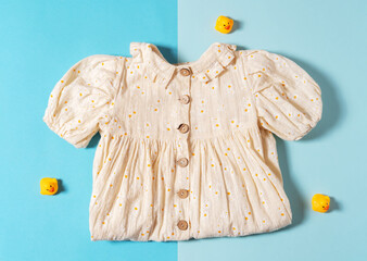 Top view natural kid dress and yellow rubber ducks on blue background.