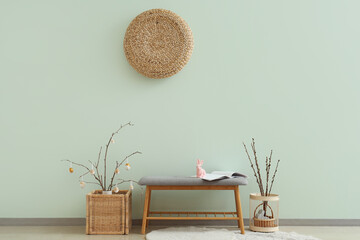 Interior of room with soft bench, tree branches and Easter eggs - obrazy, fototapety, plakaty